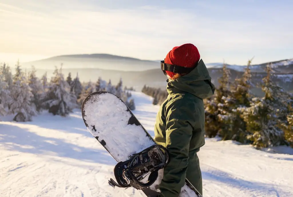 Woman with snowboard on a mountain. A habit tracker can help you change your life.